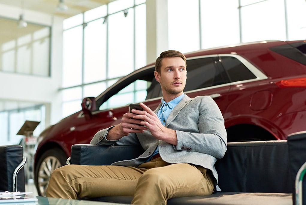 Man on phone waiting in car dealership