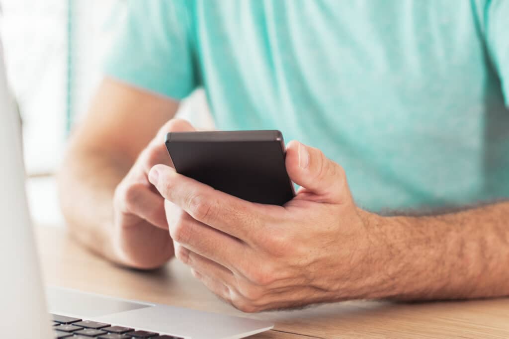 Man using his phone as a MFA device for logging into his computer on his desk